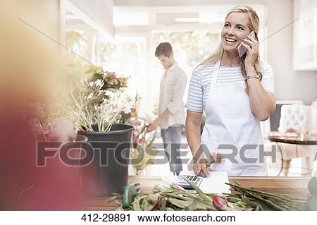 Smiling florist talking on cell phone in flower shop View Large Photo Image Stock Image - Smiling florist talking on cell phone in flower shop. Fotosearch