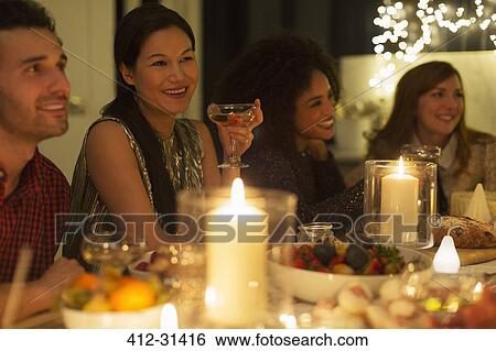 Smiling friends drinking champagne at candlelight Christmas dinner View Large Photo Image Stock Photograph - Smiling friends drinking champagne at candlelight Christmas dinner. Fotosearch