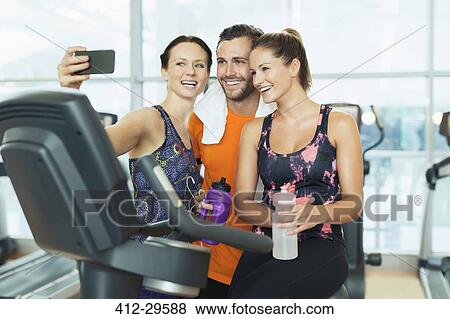 Smiling friends taking selfie at exercise bike in gym View Large Photo Image Stock Photo - Smiling friends taking selfie at exercise bike in gym. Fotosearch