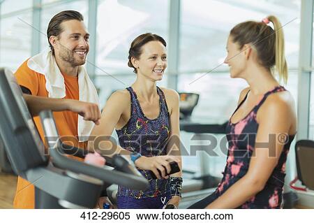 Stock Photography - Smiling friends talking at gym. Fotosearch