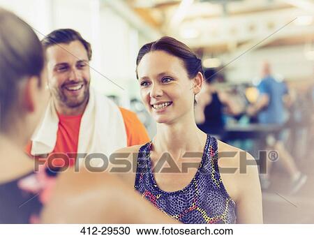 Stock Image - Smiling friends talking in gym. Fotosearch