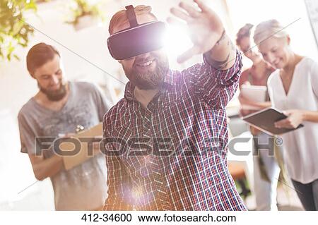 Stock Image - Smiling male design professional using virtual reality simulator glasses in meeting. Fotosearch