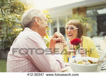 Smiling mature couple enjoying lunch in garden View Large Photo Image Stock Photo - Smiling mature couple enjoying lunch in garden. Fotosearch