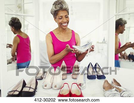 Smiling mature woman looking at high heels in closet View Large Photo Image Stock Image - Smiling mature woman looking at high heels in closet. Fotosearch
