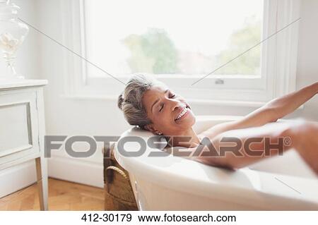Stock Photo - Smiling mature woman with eyes closed enjoying bath. Fotosearch