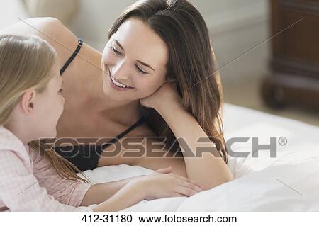 Smiling mother and daughter talking on bed View Large Photo Image Stock Image - Smiling mother and daughter talking on bed. Fotosearch