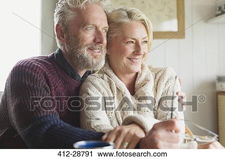 Stock Image - Smiling senior couple hugging and looking away. Fotosearch