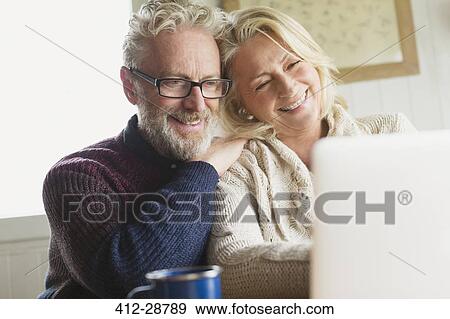 Smiling senior couple using laptop in kitchen View Large Photo Image Stock Photo - Smiling senior couple using laptop in kitchen. Fotosearch