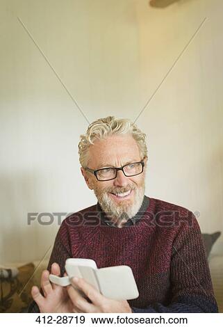 Stock Photo - Smiling senior man texting with cell phone. Fotosearch