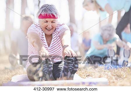 Smiling senior woman stretching in yoga class View Large Photo Image Stock Photo - Smiling senior woman stretching in yoga class. Fotosearch
