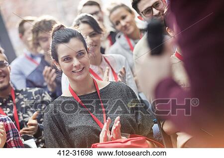 Stock Photo - Smiling woman in audience clapping at conference. Fotosearch