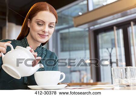 Smiling woman pouring tea in cafe View Large Photo Image Stock Photo - Smiling woman pouring tea in cafe. Fotosearch