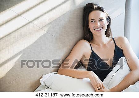 Stock Photo - Smiling woman relaxing in morning bed. Fotosearch