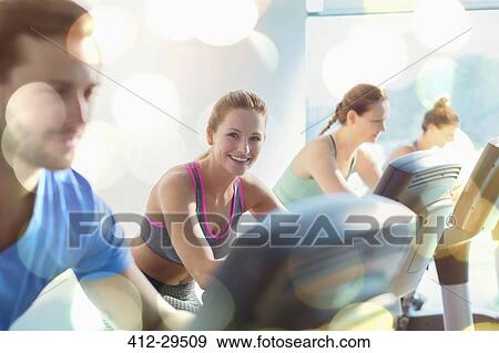 Smiling woman riding exercise bike at gym View Large Photo Image Stock Photo - Smiling woman riding exercise bike at gym. Fotosearch