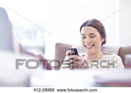 Stock Photo - Smiling woman texting with cell phone. Fotosearch