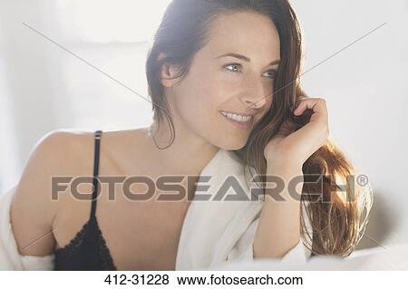 Stock Photo - Smiling woman with hand in hair looking away. Fotosearch