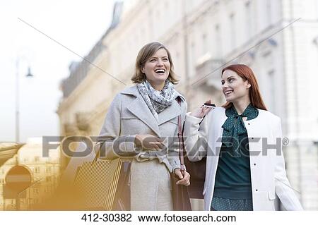Smiling women carrying shopping bags in city View Large Photo Image Stock Image - Smiling women carrying shopping bags in city. Fotosearch