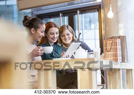 Smiling women drinking tea and sharing digital tablet at cafe counter View Large Photo Image Stock Image - Smiling women drinking tea and sharing digital tablet at cafe counter. Fotosearch