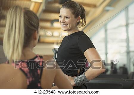 Stock Image - Smiling women talking at gym. Fotosearch