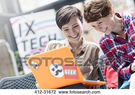 Stock Image - Smiling women using laptop at technology conference. Fotosearch