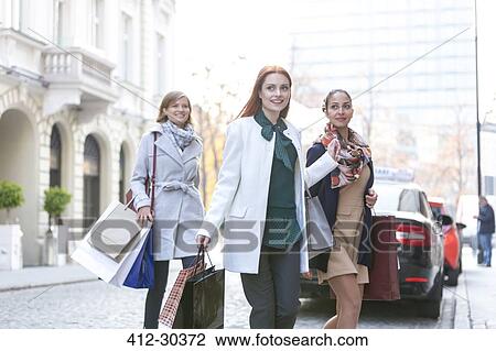 Smiling women with shopping bags crossing city street View Large Photo Image Stock Image - Smiling women with shopping bags crossing city street. Fotosearch