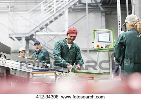 Stock Photo - Smiling worker at conveyor belt in food processing plant. Fotosearch