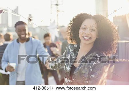 Smiling young couple holding hands at rooftop party View Large Photo Image Stock Photo - Smiling young couple holding hands at rooftop party. Fotosearch