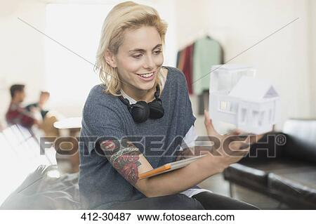 Stock Photo - Smiling young tattooed female architect holding model. Fotosearch
