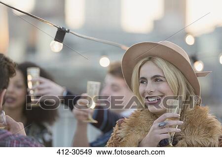 Smiling young woman drinking champagne at party View Large Photo Image Stock Photo - Smiling young woman drinking champagne at party. Fotosearch