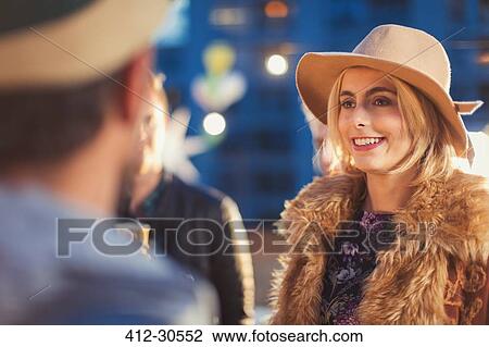 Stock Image - Smiling young woman socializing at party. Fotosearch