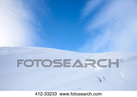 Stock Image - Snow-covered hill under blue sky. Fotosearch