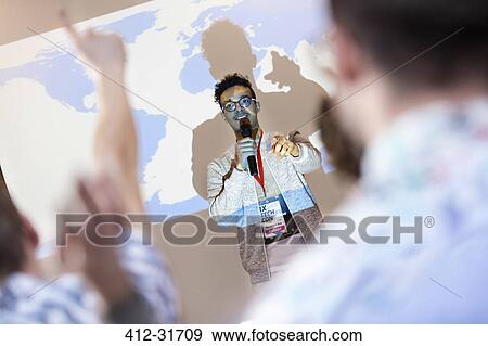 Speaker at projection screen answering questions at technology conference View Large Photo Image Stock Photo - Speaker at projection screen answering questions at technology conference. Fotosearch