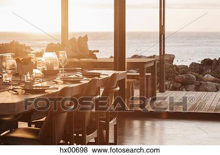 Sunny home showcase dining room overlooking ocean at sunset View Large Photo Image Stock Photo - Sunny home showcase dining room overlooking ocean at sunset. Fotosearch