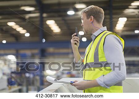 Supervisor using walkie-talkie in steel factory View Large Photo Image Stock Photo - Supervisor using walkie-talkie in steel factory. Fotosearch