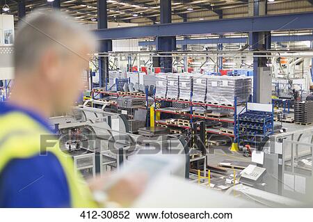 Stock Image - Supervisor with digital tablet overlooking steel factory. Fotosearch