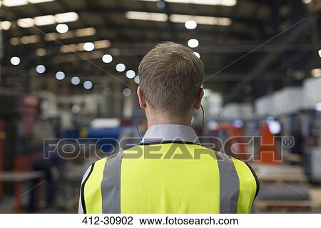 Stock Image - Supervisor with earplugs watching steel factory. Fotosearch
