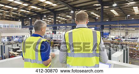 Stock Image - Supervisors on platform above steel factory. Fotosearch