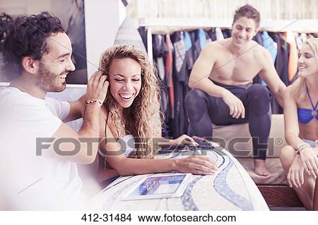 Picture - Surfers hanging out listening to music with headphones and digital tablet. Fotosearch