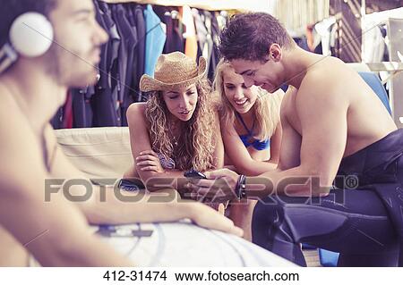 Surfers hanging out texting with cell phone View Large Photo Image Picture - Surfers hanging out texting with cell phone. Fotosearch