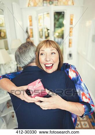 Surprise mature woman receiving gift from husband View Large Photo Image Stock Image - Surprise mature woman receiving gift from husband. Fotosearch