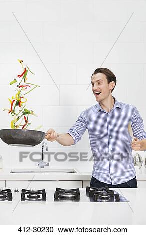 Surprised couple cooking and flipping vegetables in skillet in kitchen View Large Photo Image Stock Image - Surprised couple cooking and flipping vegetables in skillet in kitchen. Fotosearch