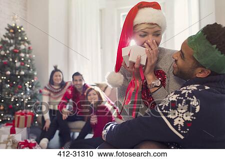 Surprised girlfriend opening Christmas gift from boyfriend View Large Photo Image Stock Image - Surprised girlfriend opening Christmas gift from boyfriend. Fotosearch