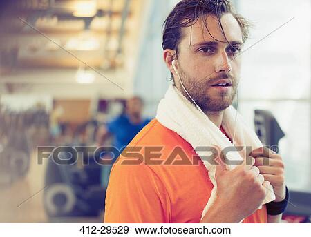 Sweating man with towel and headphones resting in gym View Large Photo Image Stock Photo - Sweating man with towel and headphones resting in gym. Fotosearch