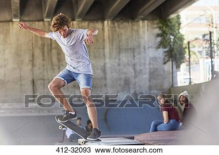 Stock Image - Teenage boy doing skateboard stunt at skate park. Fotosearch