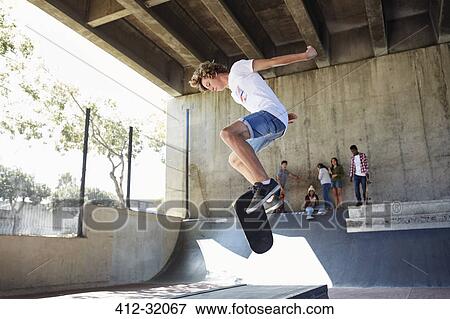 Teenage boy flipping skateboard at skate park View Large Photo Image Stock Photo - Teenage boy flipping skateboard at skate park. Fotosearch