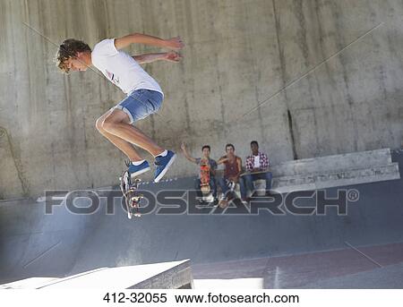 Stock Photography - Teenage boy flipping skateboard at skate park. Fotosearch