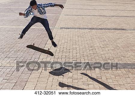 Teenage boy flipping skateboard on sunny cobblestone View Large Photo Image Stock Image - Teenage boy flipping skateboard on sunny cobblestone. Fotosearch