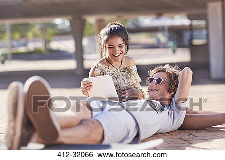 Teenage couple hanging out using digital tablet View Large Photo Image Stock Photograph - Teenage couple hanging out using digital tablet. Fotosearch
