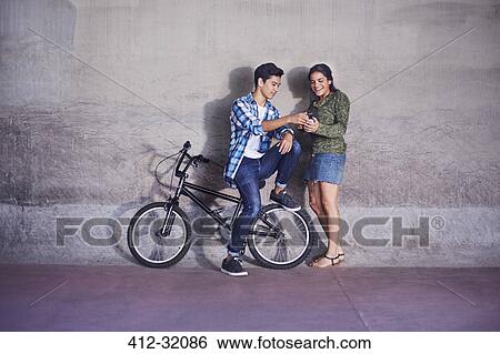 Stock Photograph - Teenage couple with BMX bicycle texting at wall. Fotosearch