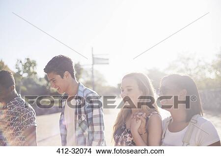 Picture - Teenage friends hanging out at sunny park. Fotosearch